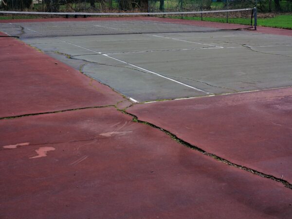 Tennis Courts - Neglected courts with cracks and debris.